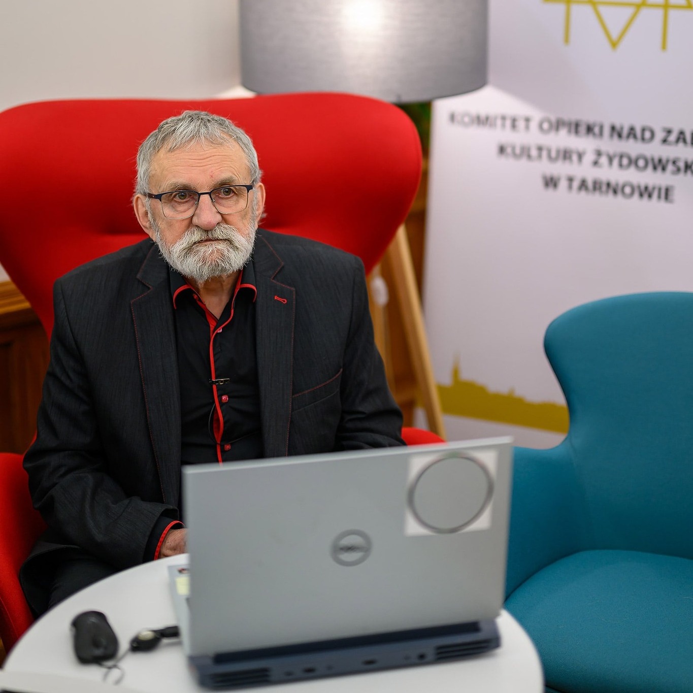 Starszy mężczyzna siedzący w czerwonym fotelu