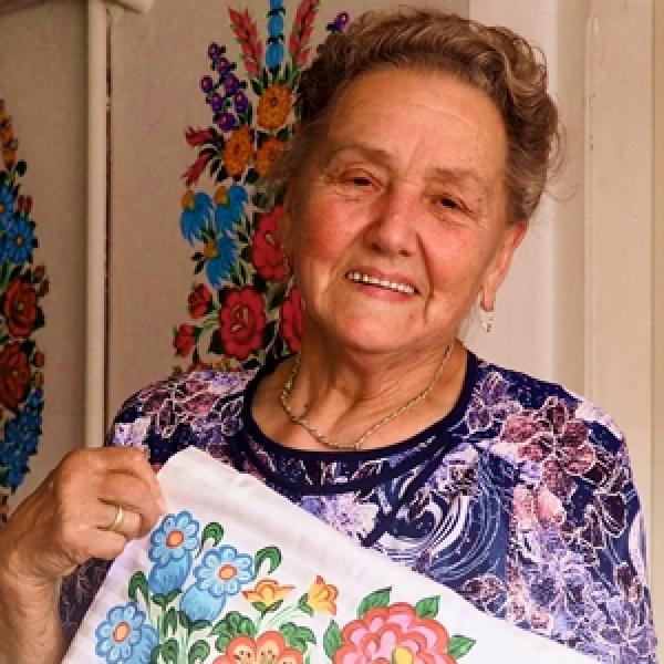 Bernadetta Słota trzyma tkaninę z malowanym bukietem