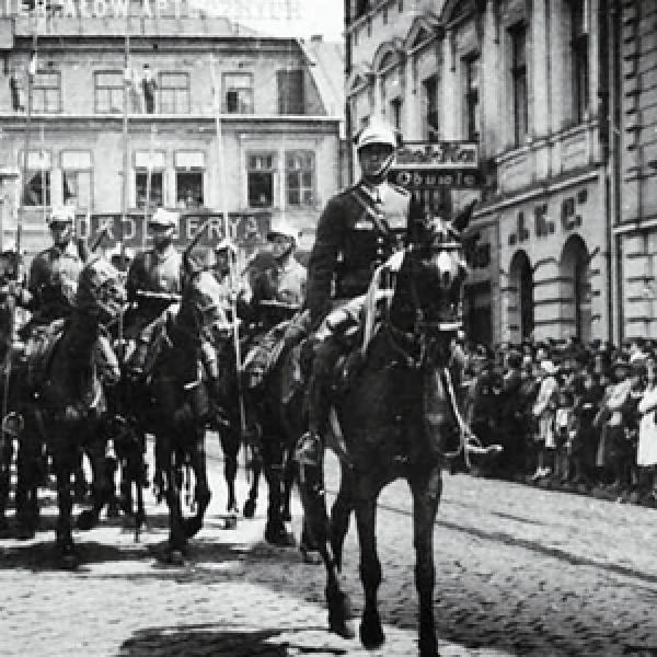 fragment plakatu przedstawiający archiwalne zdjęcie z paradą konną  na ulicy Krakowskiej w Tarnowie